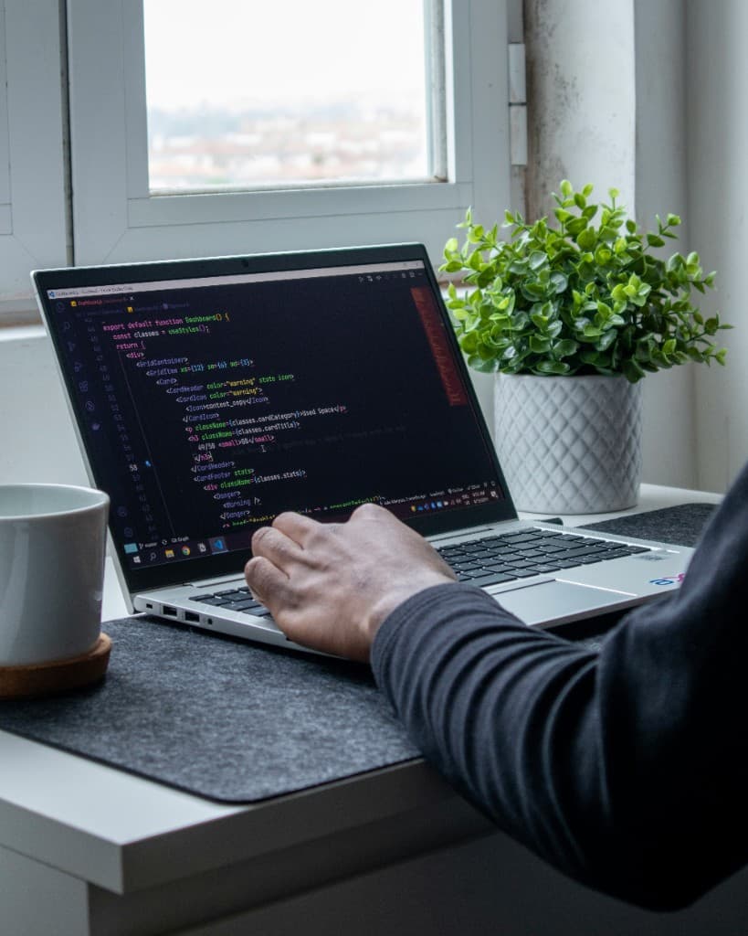 Developer reviewing code on a laptop at a bright desk